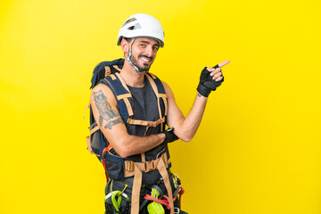 Young caucasian rock climber man isolated on yellow background pointing finger to the side