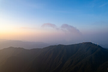 Jiugong Mountain in Xianning City, China features wind turbines on its peaks during a sunset.