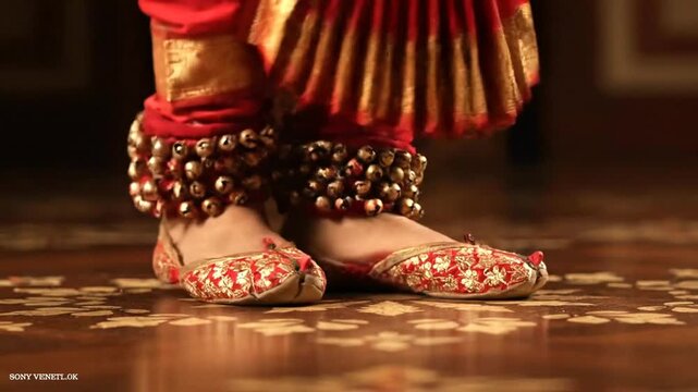 A close-up of an Indian classical dancer's feet adorned with ghungroo ankle bells and embroidered shoes.