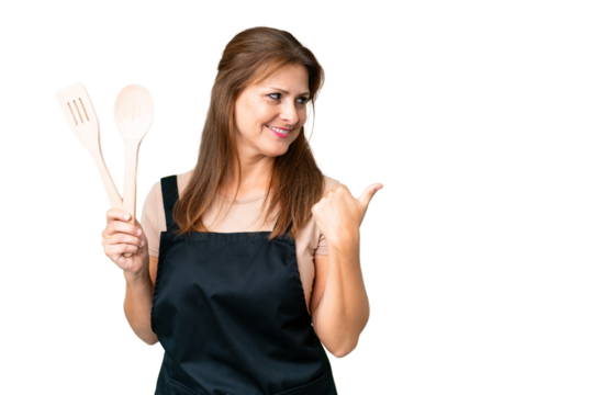 Middle age caucasian woman holding a rolling pin over isolated background pointing to the side to present a product