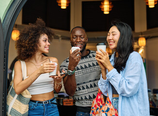 Portrait of group of young people drinking coffee in coffee shop city street, walking together and having fun.