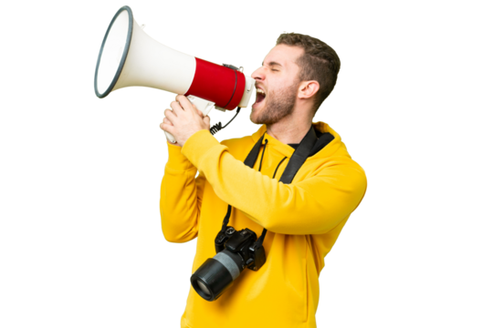 Young photographer man over isolated chroma key background shouting through a megaphone