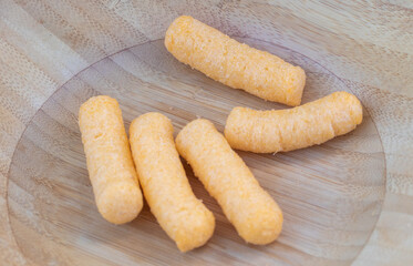 Cheese Corn Puffs Snack on Wooden Plate Closeup