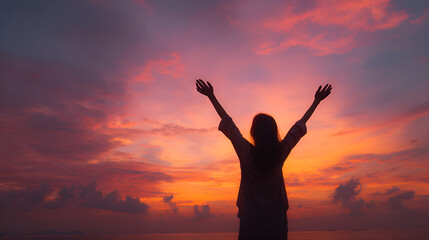 Fototapeta premium Woman raising hands at sunset, feeling freedom and happiness