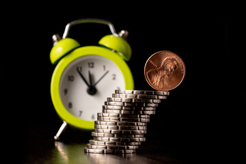 A US 1 cent coin on the edge of a slanted stack of coins