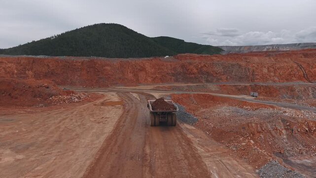 Aerial view dump truck is transporting gold and copper ore into in open pit mine, mining industry.