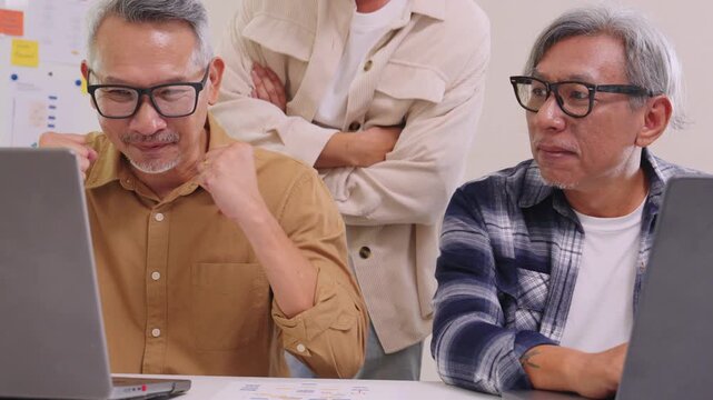 Senior developer team celebrates success in software collaboration and coding at a modern computer workstation