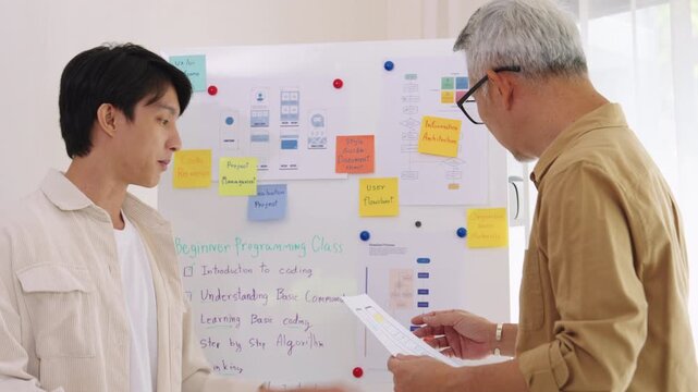senior programmer bootcamlp,Asian young instructor guides senior learners through a programming on whiteboard, highlighting algorithm thinking and simple code exercises