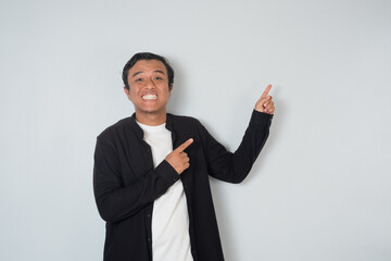 An Asian man smiles and points upwards, showing a cheerful and confident expression. Concept of...