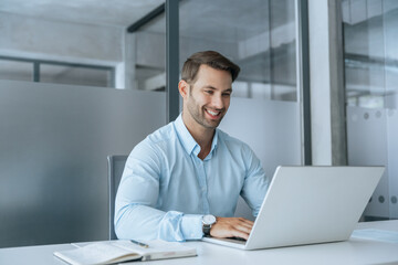 European businessman ceo specialist using computer technology app for work online. Young professional specialist latin hispanic businessman working on laptop pc sitting at desk in modern office space