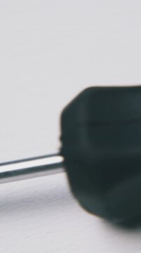 new crosshead screwdriver with red and black plastic handle lies on white background extreme close view