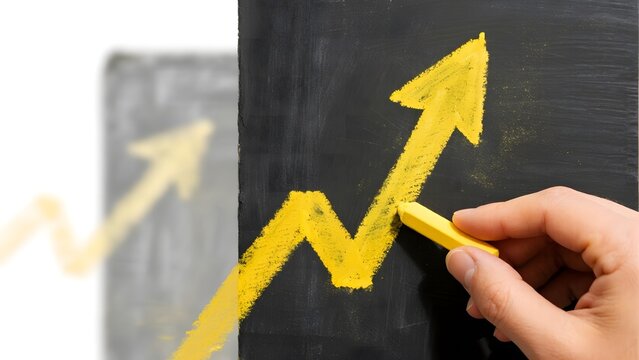 Hand drawing a yellow upward arrow on a blackboard, symbolizing growth or progress. - Powered by Adobe