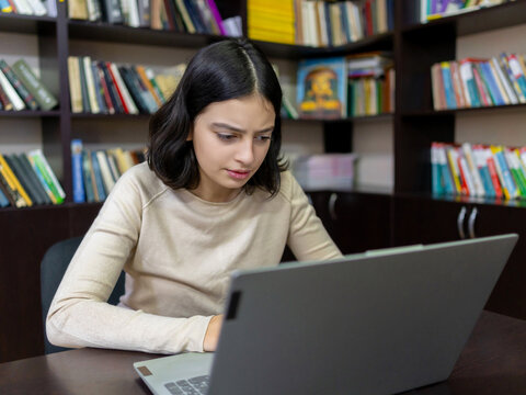 Teenage school girl working on a computer in the library
