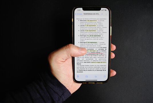 Mano con tel&eacute;fono m&oacute;vil, p&aacute;rrafo de texto en documento de letras y palabras con fondo negro