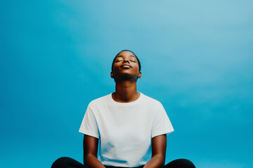 A person sits in a relaxed position eyes closed on blue background, generated AI