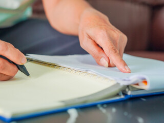 Close-up senior woman hand taking notes income and expenses. Retirement planning to save money. Saving earnings in a piggy bank. Lifestyle people concept retired life, financial or account economy 