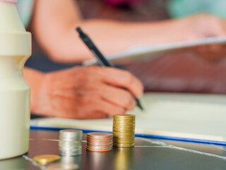 Fototapeta premium Close-up senior woman hand taking notes income and expenses. Retirement planning to save money. Saving earnings in a piggy bank. Lifestyle people concept retired life, financial or account economy 