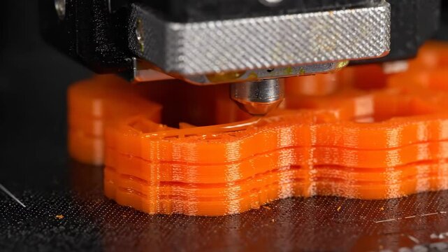 Orange Plastic Being Created Layer by Layer Using a 3D Printer at Home During the Day, Build Process Shown up Close