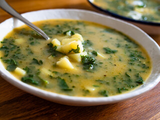 Portuguese green soup - Caldo Verde. Potato and kale soup on wooden table	
