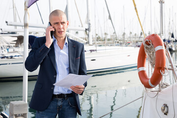 Man businessman communicates on a mobile phone with in the port near