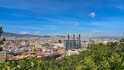 Scenic panoramic view of Barcelona with urban architecture, city rooftops and distant hills under clear sky. Travel destination and tourism background