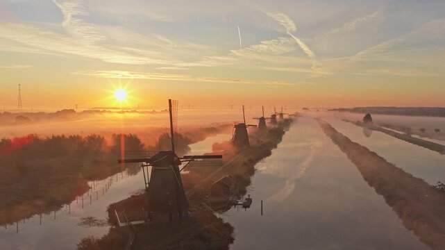 Sunrise drone video of Kinderdijk iconic windmills with soft fog, Holland