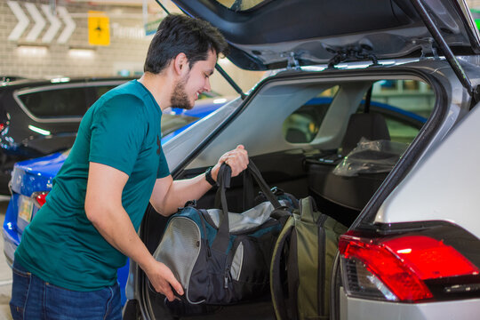 Traveler loading luggage into car trunk inside parking garage symbolizing tourism, mobility, vacation preparation, urban lifestyle, car rental, commuting and modern transport experience in the city - Powered by Adobe