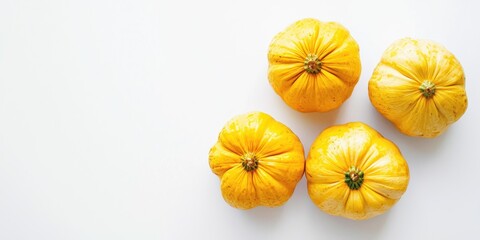 Three small, bright yellow pumpkins are arranged on a white surface. The pumpkins have a smooth, slightly textured skin and a dark green stem. The background is plain white, creating a clean 