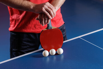 Table tennis paddle with balls on blue table serve preparation closeup