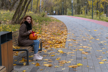 Young woman enjoying a quiet autumn day in the park with a pumpkin
