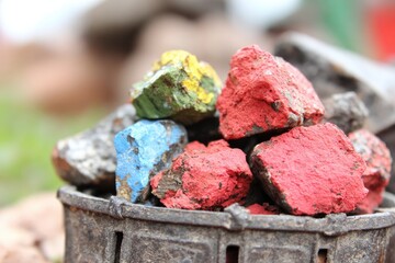 Colorful painted rocks in a dark metal container