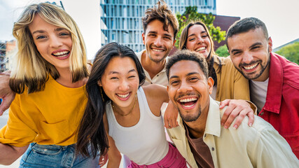 Fototapeta na wymiar Happy multiracial friends having fun on city street - Group of young people smiling at camera outside - Friendship concept with guys and girls walking in downtown road