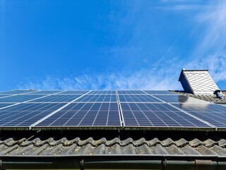 Solar panels providing sustainable energy on a house roof under blue sky