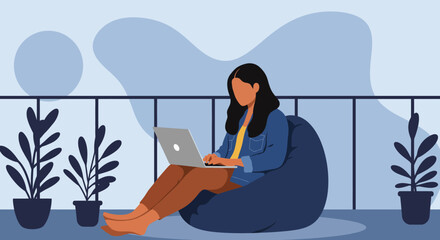 Woman working remotely on a laptop, comfortably seated on a bean bag on a modern balcony with potted plants. Represents flexible work, freelance, or online learning lifestyle.