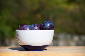 a bowl of plums on a table