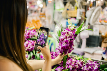 Tourist taking photos of orchids at bangkok flower market