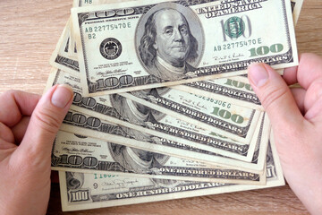 hand with magnifying glass checking 100 USA dollar banknote on money background, exchange money