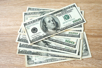 pile of 100 USA dollar banknotes on wooden background, exchange money, closeup