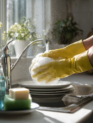 Hands Washing Dishes in Bright Yellow Gloves with Soap Suds