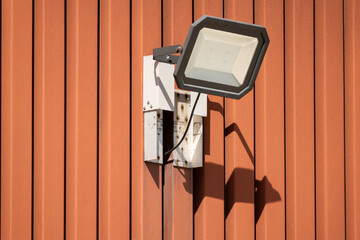 Electrical LED lamp at the outside of a corrugated wall of a company building. Shot at daylight,...