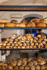 Vertical photography of Rustic artisan bakery with shelves full of fresh sourdough loaves and rolls. Warm natural light, authentic atmosphere, perfect for healthy food and bakery concepts.