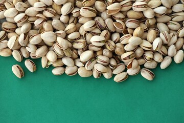 Tasty unpeeled pistachios on bright green background, top view flat lay background pattern