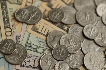 Many different dollar bills and silver cent coins under natural light