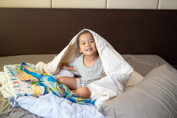Adorable kindergarten kid girl wake up and enjoy play blanket