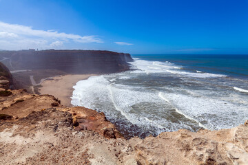 A breathtaking coastal panorama with powerful waves crashing onto a sandy beach