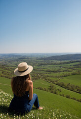 Fototapeta premium Woman with hat looking at spring landscape from hill