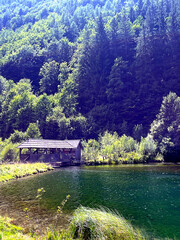 Wooden hut by an emerald-green alpine lake surrounded by forest in Turnau, Austria. Peaceful natural landscape perfect for travel and nature themes.