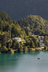 Fototapeta premium Scenic view of Lake Bled in Slovenia with a white villa on the forested shore, turquoise water, and wooded hills in the background.