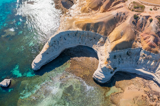 Aerial view of a crescent shaped cove below rugged eroded cliffs at Maslin Beach, South Australia