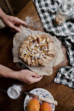 peach tart with hands on a timber tabletop
